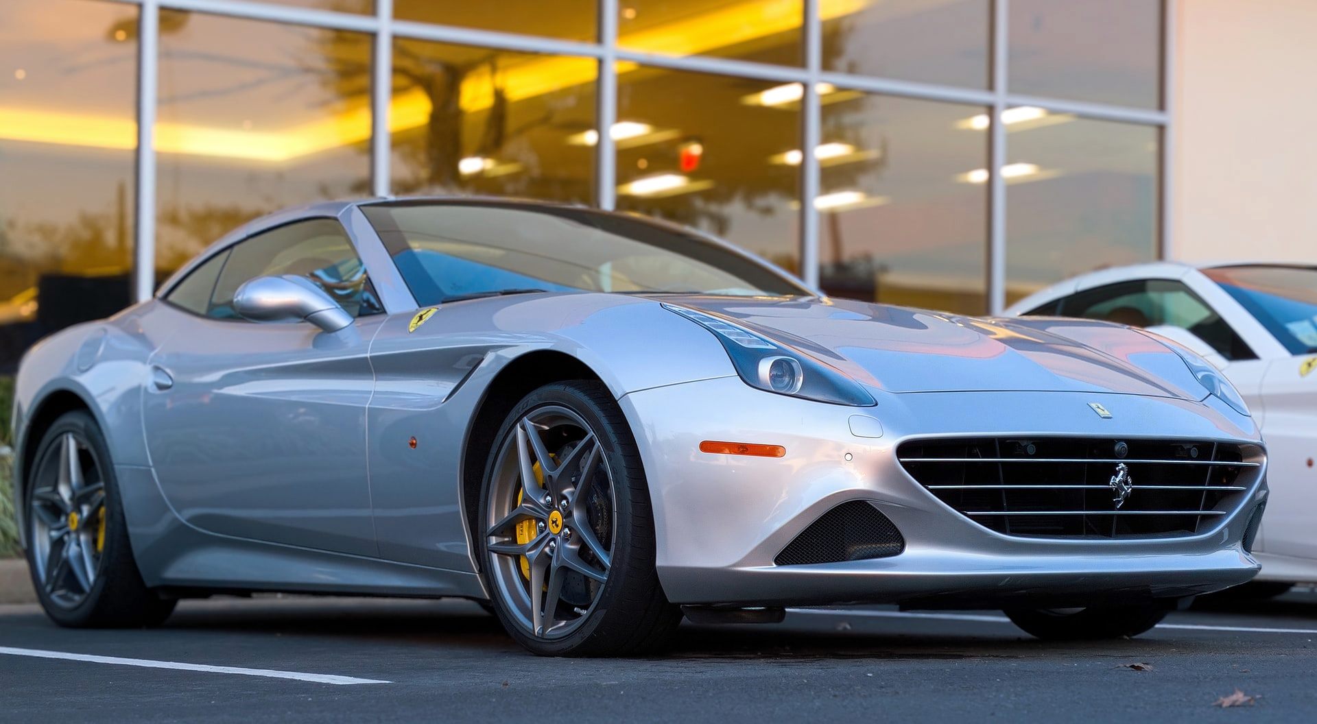A silver ferrari is parked in front of a building.