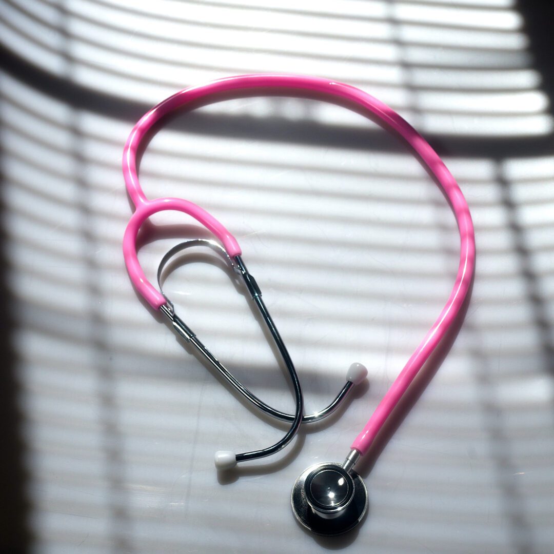 A pink stethoscope sitting on top of a table.