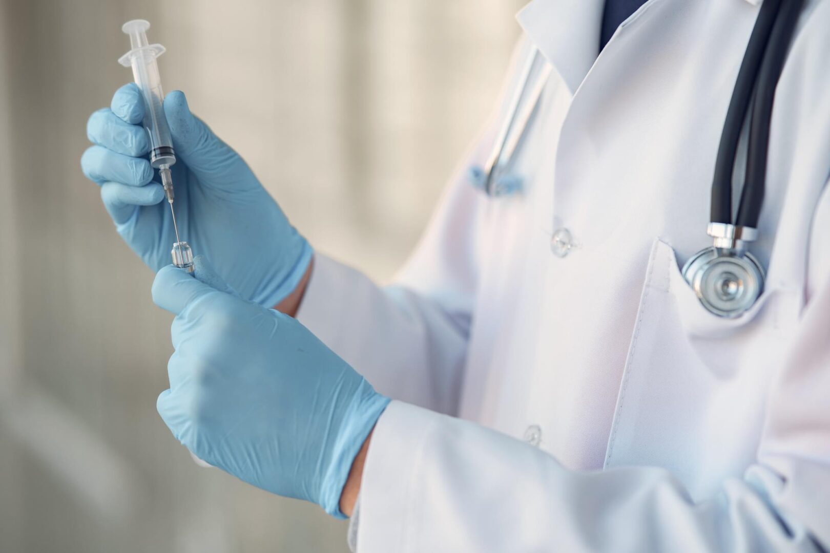 A person in white lab coat holding a syringe.