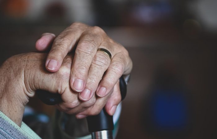 A close up of an elderly person 's hands on top of a cane.