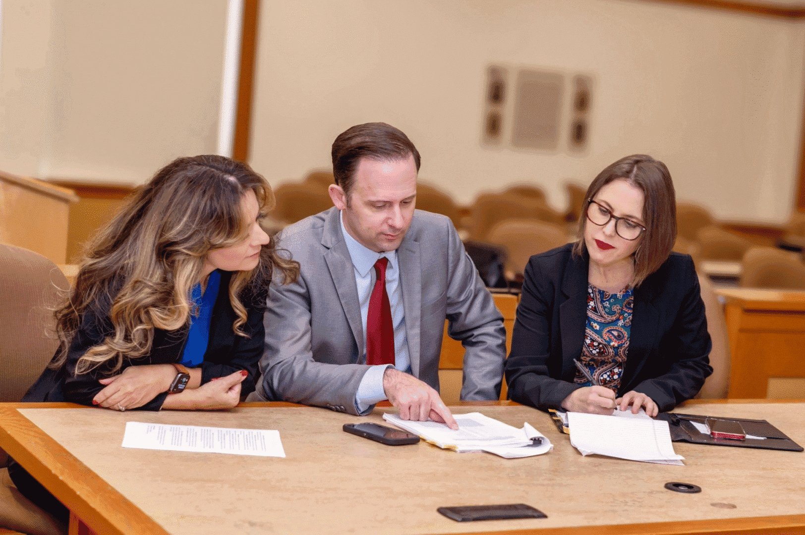 Three people discussing documents at table.